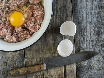 Directly above shot of minced meat with egg yolk in bowl by knife on table