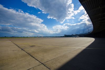 Empty airport runway against cloudy sky