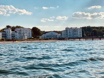 Houses by sea against sky in city