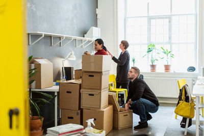 Multi-ethnic colleagues working by cardboard boxes stack at creative office