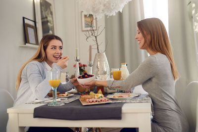 Smiling young friends eating lunch at home