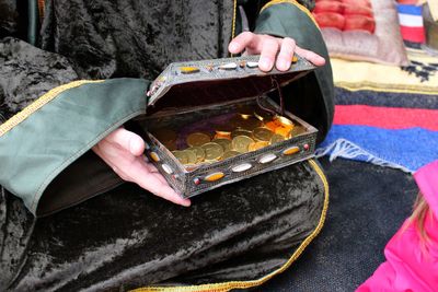 Midsection of person holding coins in box