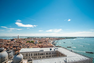 High angle view of townscape by sea against blue sky