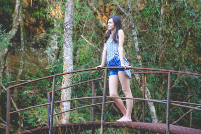 Woman standing on footbridge in forest