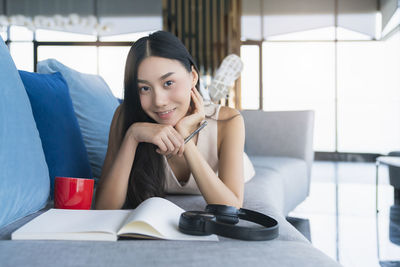 Portrait of smiling young woman sitting on book