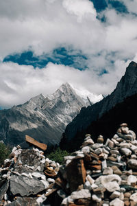 Stack of rocks on snow covered mountain against sky