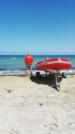 Rear view of man on beach against blue sky