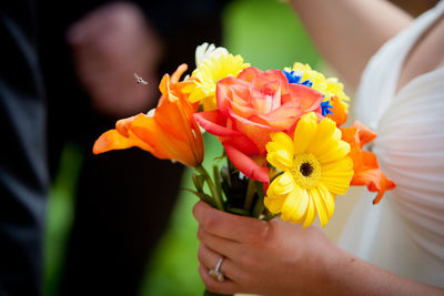 Cropped image of bride holding flowers during wedding ceremony