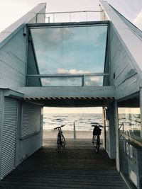 People riding bicycle on bridge against buildings