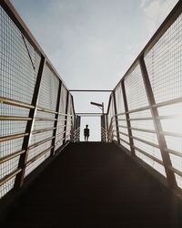 Rear view of silhouette people walking on footbridge