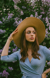 Portrait of beautiful young woman standing against plants