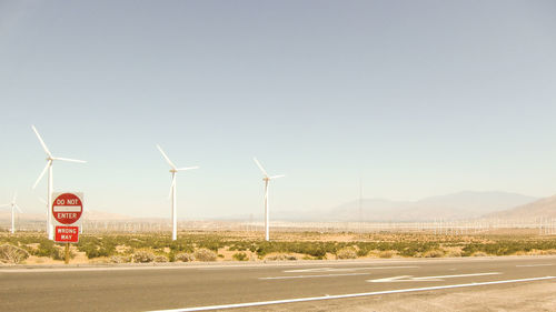 Windmills on road against sky