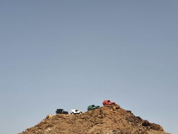 Low angle view of rocks against clear sky and car art in flag colour 