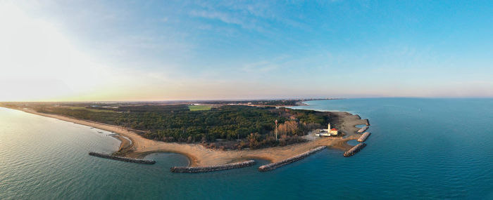 Bibione lighthouse from above at sunset in a panoramic aerial view	with sea and blue sky