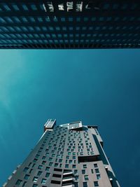 Low angle view of skyscraper against blue sky