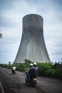 Rear view of people riding motorcycle on road against sky