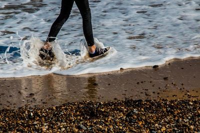 Low section of woman walking in sea