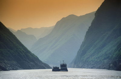Boats in river against mountains