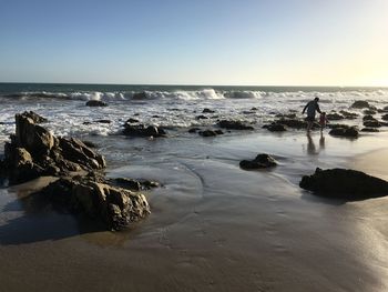 Father and son walking on shore at beach