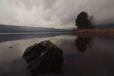 Rocks by lake against sky