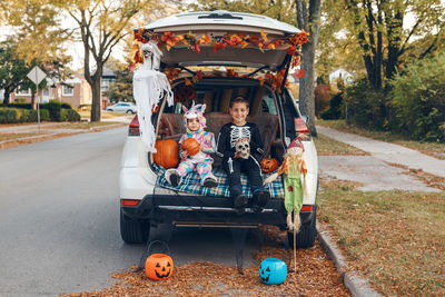 Cute kids wearing costume sitting in car trunk