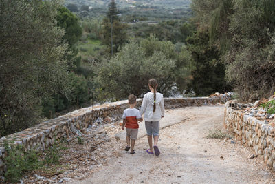 Rear view of women walking on road amidst trees