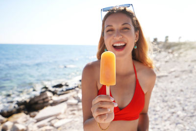 Attractive young woman offers a popsicle at the camera on summer. focus on popsicle.