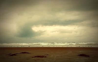 Scenic view of beach against cloudy sky