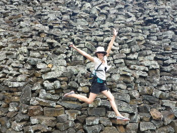 Cheerful woman jumping against wall of tears