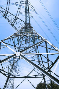 Low angle view of electricity pylon against blue sky