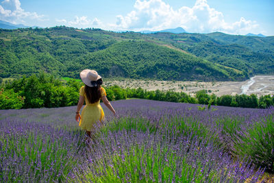 Full length of woman standing on field against cloudy sky