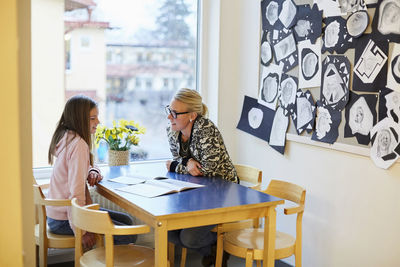 Mid adult teacher teaching middle school girl at desk