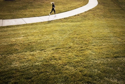 Athlete jogging on pathway amidst grassy field