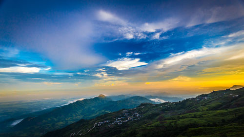 Scenic view of landscape against dramatic sky during sunset