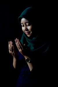 Young woman wearing mask against black background