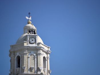 Low angle view of bell tower against clear blue sky