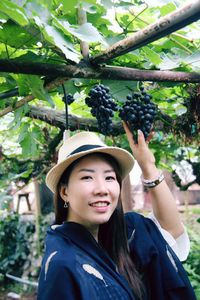 Portrait of smiling young woman against tree