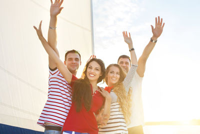 Happy young woman with arms raised against the sky