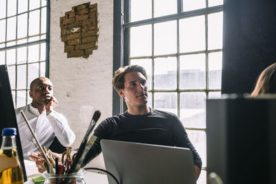 Confident male it professionals looking away while sitting in board room during meeting