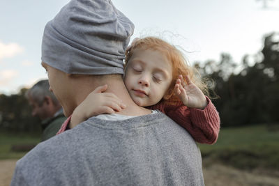 Father carrying daughter with eyes closed