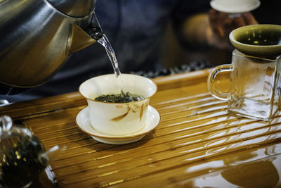 Midsection of person pouring water in cup