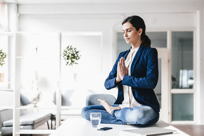 Businesswoman sitting on table meditating