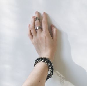 Cropped hand of woman wearing finger rings and bracelet while touching white wall