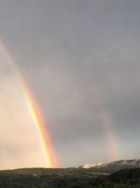 Scenic view of rainbow over mountain against sky