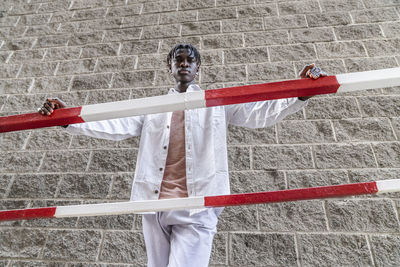 Young man with dreadlocks standing by railing