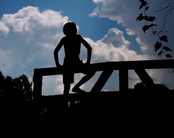 Low angle view of silhouette boy against sky