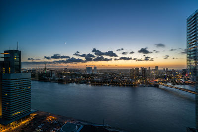 High angle view of illuminated buildings by river during sunset