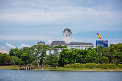 View of trees and buildings against cloudy sky