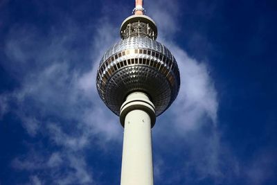 Low angle view of communications tower against cloudy sky