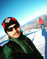 Portrait of man in snow covered mountains against clear sky